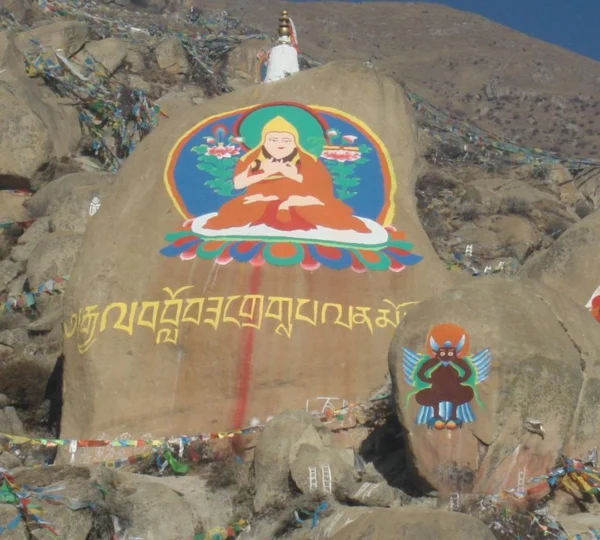 Traditional Buddhist deities painted on large rocks surrounded by prayer flags near Drepung Monastery in Lhasa, Tibet.