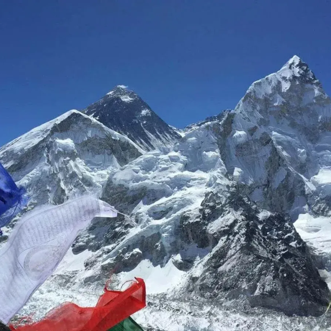 Colorful prayer flags at Everest Base Camp with snow-covered Himalayan peaks under a clear blue sky